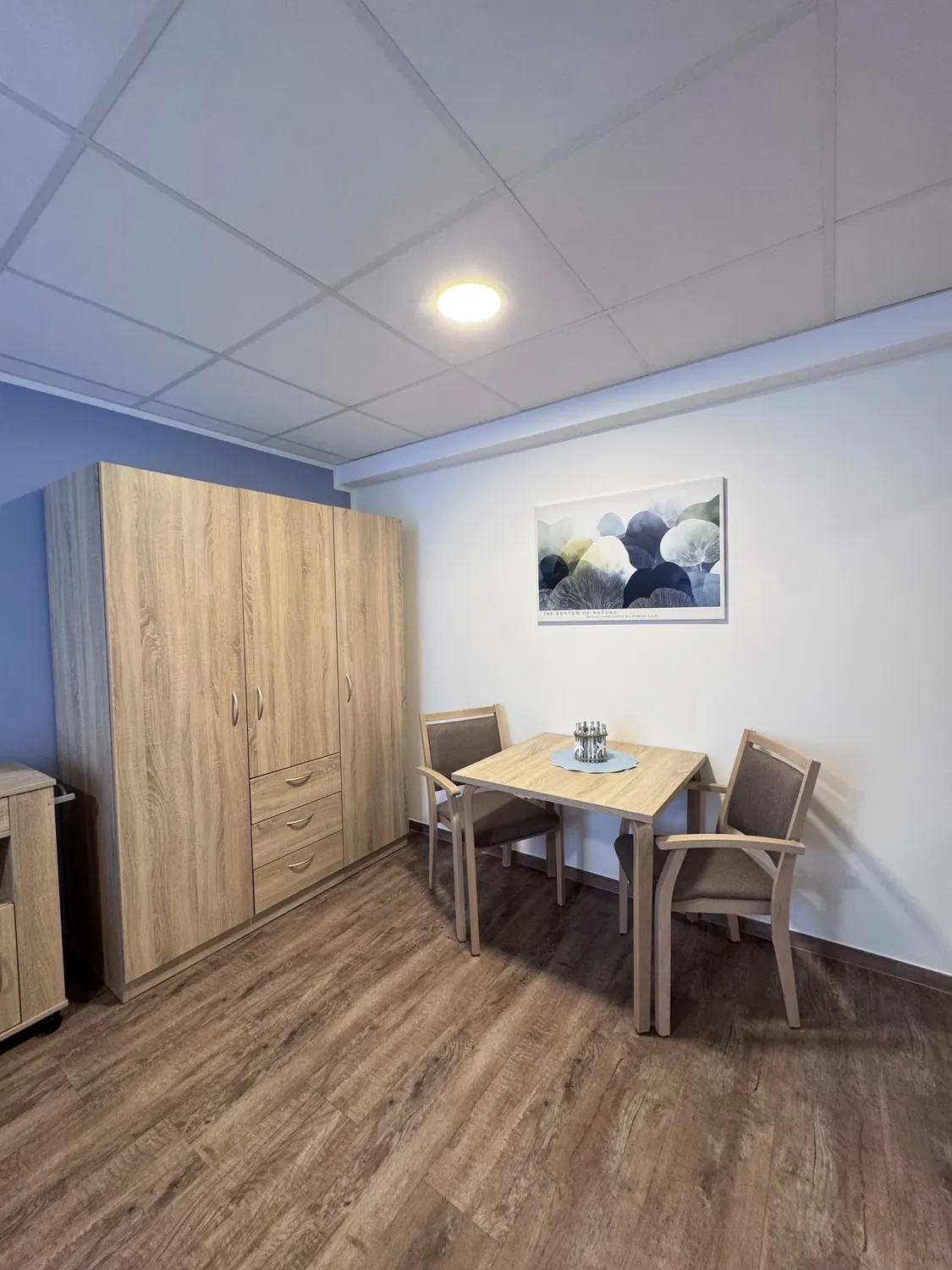 Curanus GmbH – Pflege – Szene: Familie hält die Hände eines sterbenden älteren Patienten, der mit Sauerstoff und Infusion im Bett liegt.